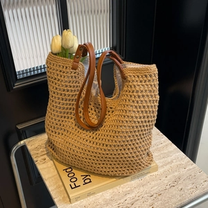 Close-up of woven tote bag showing leather straps and net texture over a book