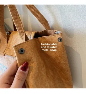 Detail of metal snap fastener on a brown wrinkled Tyvek commute bag with blue letters