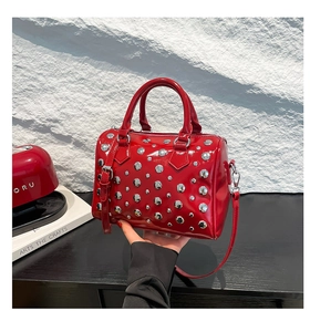Detailed view of red patent leather Boston bag featuring metallic silver stud accents