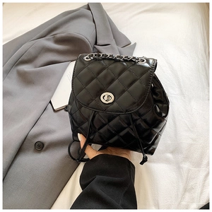 Detail of black quilted leather backpack with silver turn-lock and chain handle