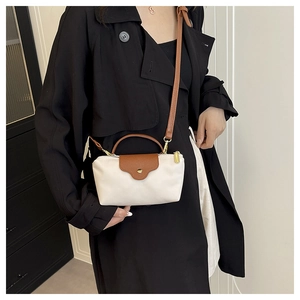 Detail of a nylon dumpling bag with beige body, brown leather flap and golden snap button