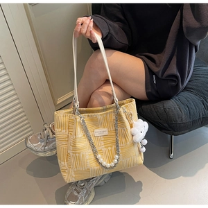 Close-up of yellow canvas tote bag with geometric texture, pearl chain, and cloud charm