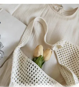 Dettaglio della borsa a spalla in maglia bianca a uncinetto con trama traforata e tracolla