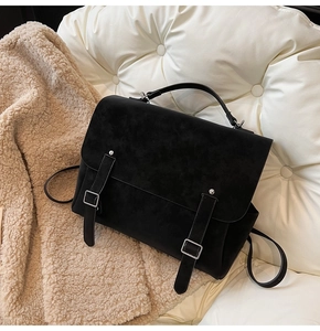 Close-up of black suede backpack featuring dual silver buckles and top handle texture