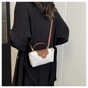 Detailed back view of a mini nylon dumpling bag with brown leather strap on a black coat