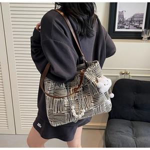 Detail of jacquard tote bag with leather straps and cloud charm accessory worn by model