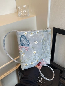 Elegant light blue embroidered crossbody bag with butterfly floral patterns on luggage