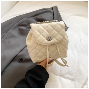 Close-up of cream white quilted mini backpack with silver chain and twist lock detail