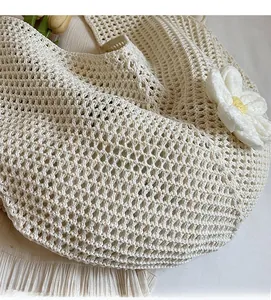 Dettaglio della borsa tote beige all'uncinetto con trama traforata e grande fiore in rilievo