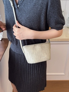 Minimalist cream woven bucket bag shown on a model in a cozy indoor lifestyle setting