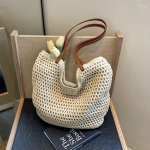 Detail of woven tote bag featuring large hollow mesh design and brown leather straps