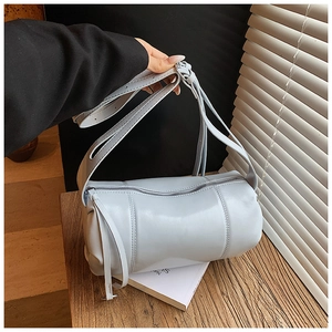 Detailed view of light blue cylinder bag with vertical stitching and silver zipper