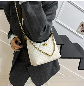 Quilted white crossbody bag with gold chain strap shown on model in minimalist setting