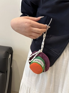 Mini hat-shaped waist pouch with vibrant colors hanging on a navy jacket pocket