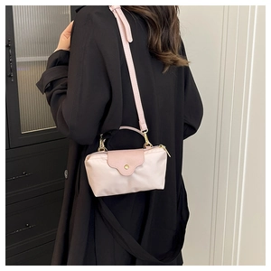 Detail of light pink nylon crossbody bag with gold hardware on a black coat background