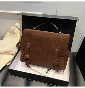 Detailed view of a vintage brown messenger bag with suede texture in a premium gift box