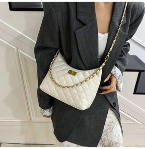 On-body view of a white quilted crossbody bag with a gold chain strap and metal lock