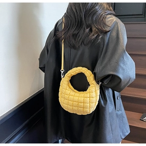 Mannequin portant un sac bandoulière matelassé jaune vif sur un manteau noir