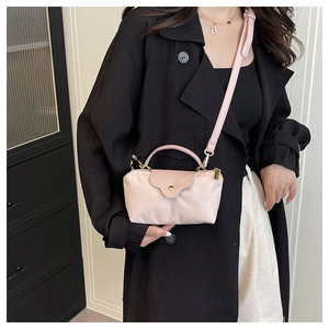 Detail of light pink nylon mini dumpling bag with leather handle and gold hardware