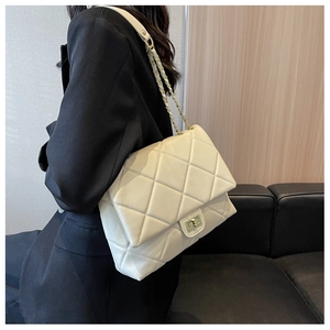 Detail view of cream quilted shoulder bag featuring gold chain strap and turn-lock closure