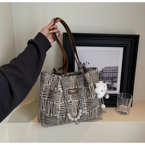 Detail of canvas tote bag with brown geometric jacquard pattern and plush cloud charm