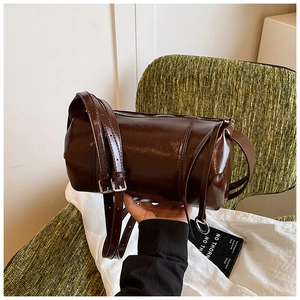 Detailed view of deep brown cylindrical Boston bag with glossy finish and silver hardware
