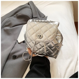 Detail of silver metallic quilted backpack featuring a polished rotating metal twist lock