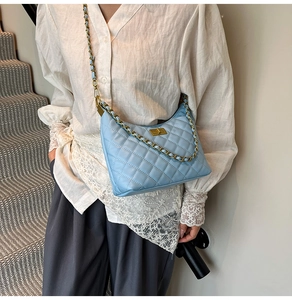 Detail of light blue quilted leather bag with gold chain strap and turn-lock closure