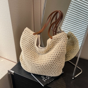 Close-up of cream woven tote bag featuring hollow mesh pattern and brown leather straps