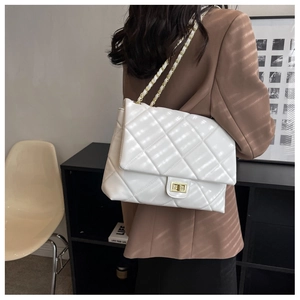 Detail of white quilted chain bag with gold metal clasp on model back view