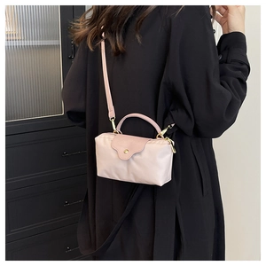 Macro view of compact champagne nylon crossbody bag featuring premium leather handle details