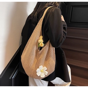 Dettaglio della borsa tote intrecciata kaki con fiore margherita all'uncinetto sulla spalla