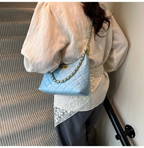 Detail of light blue quilted crossbody bag with gold chain strap on a fashion model