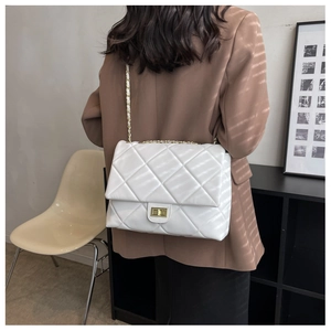 Detailed back view of a white quilted crossbody bag with gold chain strap on a model