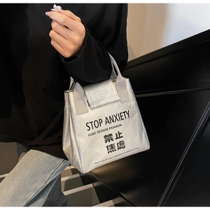 Detail of silver Tyvek tote bag featuring black Stop Anxiety print with natural texture