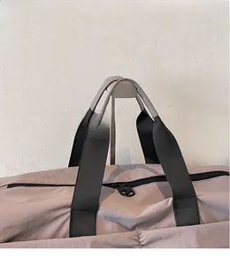 Close-up of mauve nylon travel bag featuring reinforced black woven handles and sturdy dual zippers