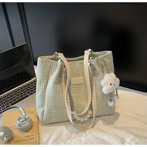 Detail of light green tote bag with texture, pearl chain and a cute cloud charm