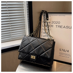 Close-up of black quilted leather bag with golden chain strap and metallic twist lock