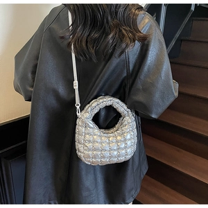 Sac à bandoulière matelassé argenté porté par un mannequin pour un look mode