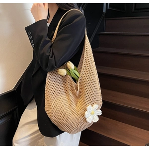 Dettaglio della borsa tote beige all'uncinetto con ciondolo a margherita su un modello