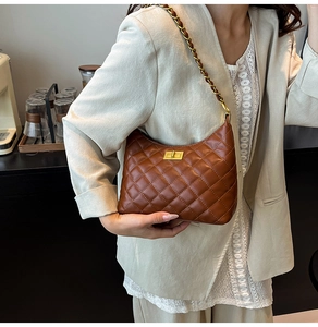 Detail of a brown quilted leather shoulder bag with gold chain strap on a model