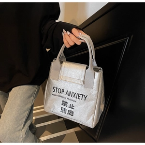 Close-up of waterproof silver Tyvek tote bag with 'STOP ANXIETY' printed text detail