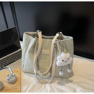Detail of light green canvas tote with pearl chain and cute plush cloud charm