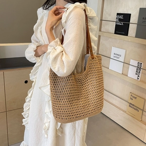 Detail of hand-woven beige tote bag showing crochet texture and brown leather strap