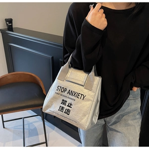 Silver DuPont paper tote bag detail featuring the Stop Anxiety slogan and crinkled texture