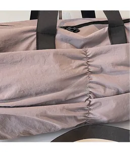 Detail shot of dusty pink nylon fabric with textured pleats and black shoulder strap