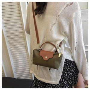 Olive green nylon crossbody bag with leather trim shown on model in indoor setting
