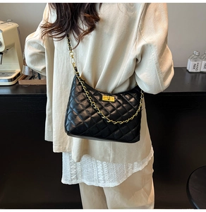 Close-up of black quilted shoulder bag with gold chain strap and turn-lock closure