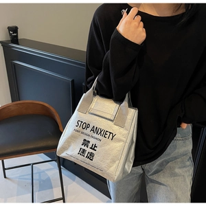 Detail of silver Dupont paper tote bag with black slogan and metallic crinkle texture