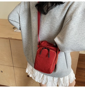 Close-up of a red waterproof nylon crossbody bag with drawstring closure and strap
